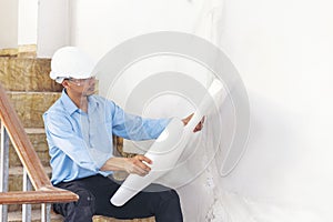 Construction engineer man hold blueprint wear blue shirt safety white hard hat at construction site industry labor worker.