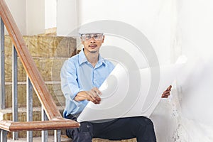 Construction engineer man hold blueprint wear blue shirt safety white hard hat at construction site industry labor worker.