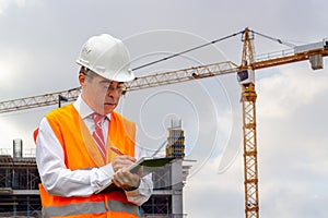 Construction engineer man in shirt and tie with safety helmet and vest works at construction site. Concept of people working in in