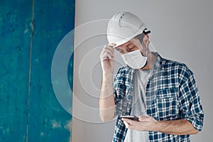 Construction engineer with protective face mask text messaging on mobile phone