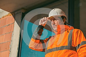 Construction engineer with protective white helmet and high visibility orange jacket on site