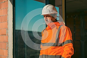 Construction engineer with protective white helmet and high visibility orange jacket on site