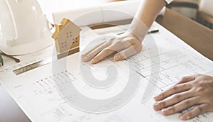 Construction engineering concept, engineering working on desk with cad drawing and safety hat and home model.