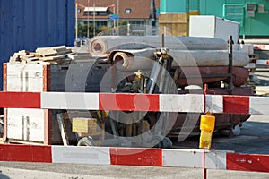 Construction equipment for civil engineering construction site bordered by barrier planks and yellow warning light