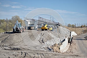 Construction equipment forms an artificial embankment and compresses the ground against the background of the construction of a