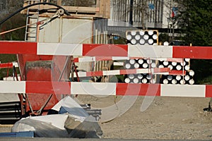 Construction equipment and material, mostly pipes, for civil engineering construction site bordered by barrier planks