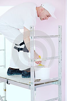 Construction finisher in white clothes with brush