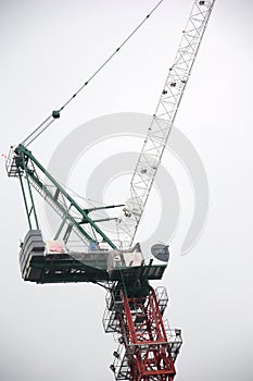 A construction fixed tower crane hoist at a construction side against a cloudless sky backdrop