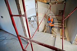 Construction foreman writing on clipboard while climbing stairs