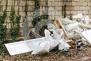 Construction garbage after apartment repair. Pile of construction waste near a white brick wall. Construction debris in white bags