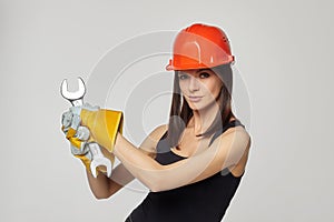 Construction girl in an orange helmet. holding a spanner. Posing while working twisting the imaginable bolt