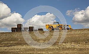 Construction grading equipment and pallets on a steep hill against a blue sky