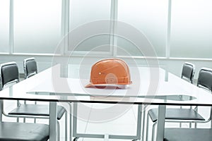 Construction hard hat and blueprints on glass table in office space