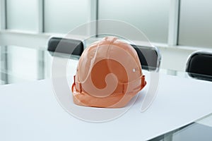 Construction hard hat and blueprints on glass table in office space
