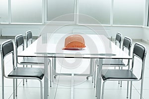 Construction hard hat and blueprints on glass table in office space