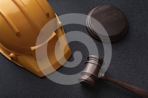 Construction helmet and judges gavel on black background. Top view. Construction law