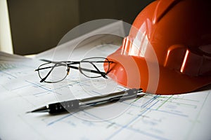 Construction helmet on the table with drawings and pencils