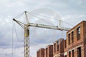 Construction of high brick house with a crane.