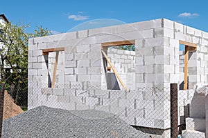 Construction of a house from gas silicate white blocks. A mountain of gravel near an unworthy house