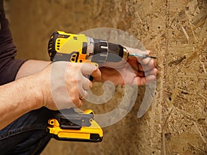 Construction of a house, a man works with a circular electric saw and an electric jigsaw