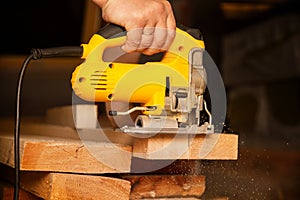 Construction of a house, a man works with a circular electric saw and an electric jigsaw