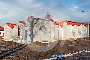 Construction of a house stopped for the winter. Aerated concrete blocks. The top of the building covered in orange plastic