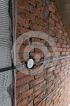 construction and improvement of a new home, black electrical wires are connected in a white junction box in a brick wall without