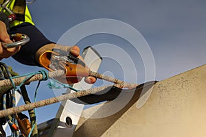 Construction industrial rope access abseiler worker standing on the safety ladder clipping fall arrester energy shock absorber photo