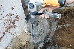 Construction industry worker using pneumatic hammer drill to cut the wall concrete brick, close up