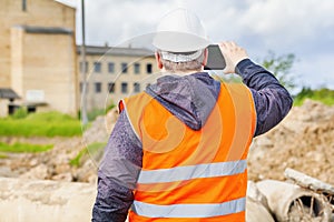 Construction inspector filming with tablet PC near building