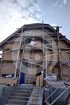 Construction and insulation of a new house with facade bricks, construction work and wooden scaffolding