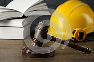 Construction and land law concepts. Gavel, hard hat, measuring tape and books on wooden table, closeup