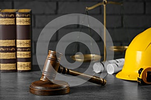 Construction and land law concepts. Judge gavel, books, protective helmet, scales of justice with drawings on grey table