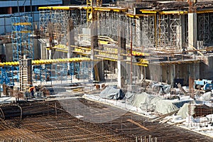 Construction of a large multi-storey commercial building. Builders work in overalls on the site pouring cement and concrete formwo