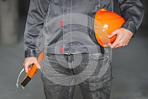 Construction level tool, safety glasses and protection helmet in the hand of a construction worker in overall. DIY or