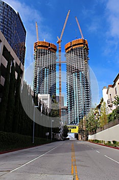 Construction lots of high-rise glass buildings with large yellow construction cranes against the blue sky.