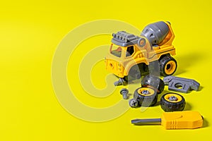 Construction machine concrete mixer made of plastic on a yellow background with a place for text copy space.