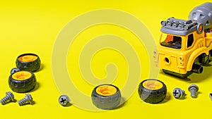 Construction machine concrete mixer made of plastic on a yellow background with a place for text copy space. Toy with cogs and