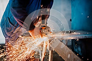 Construction male worker using electrical angle grinder for cutting iron bars