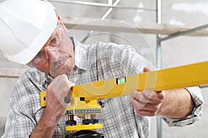 Construction man worker measure with level laser wear hard hat and protective glasses  at interior building site