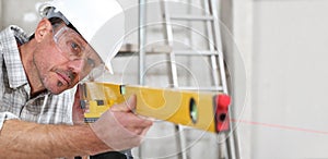 Construction man worker measure with level laser wear hard hat and protective glasses  at interior building site