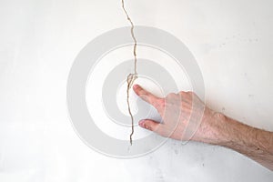 Construction man worker repairing a crack wall of a home, plastering cement on wall. Builder applying white cement to a