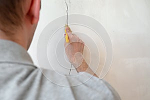 Construction man worker repairing a crack wall of a home, plastering cement on wall. Builder applying white cement to a