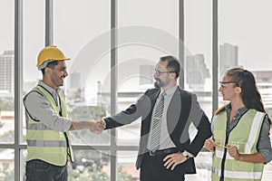 Construction manager and engineer construction in protective uniform shaking hands while working finish an agreement in the office