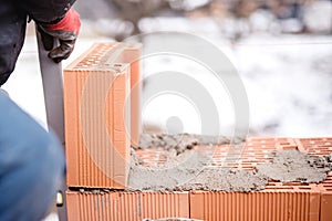 Construction mason worker bricklayer installing brick walls with trowel putty knife