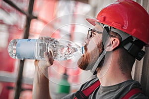 Construction mason worker on scaffolding, resting and drinking water