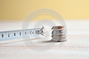 Construction measuring tape and coins on the table