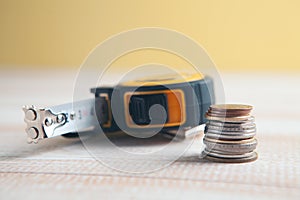 Construction measuring tape and coins on the table