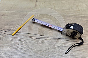 Construction Measuring Tape and pencil for working with wood products and surfaces on wooden table. Renovation planning concept.