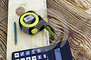 construction meter-tape measure calculator for calculations pencil and wooden board are on the workbench